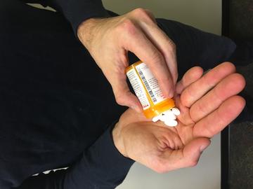 white man holding a bottle of prescription pills